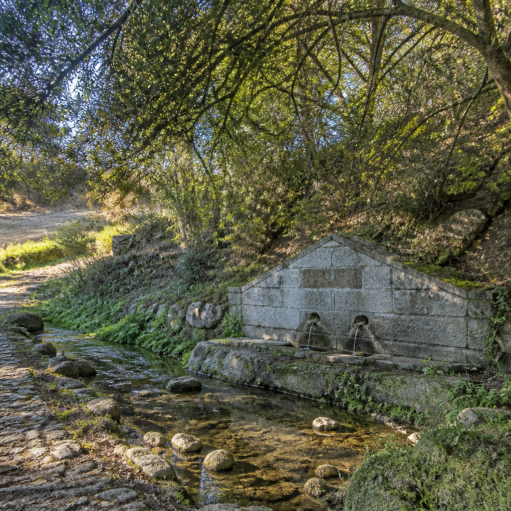Recreación ilustrativa de un arroyo junto a una fuente de granito; no es una fotografía del Caganchas ni de la Fuente del Chorrillo