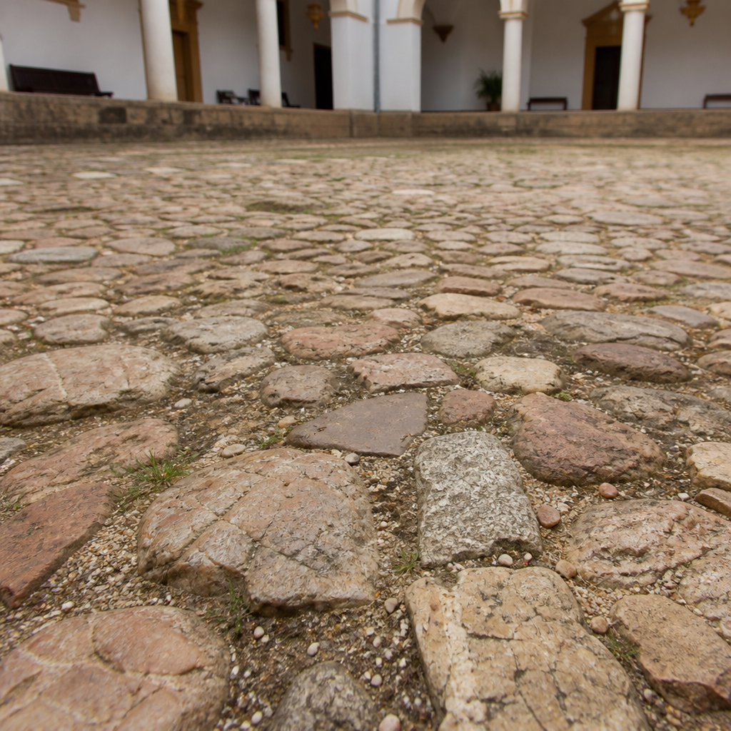 Empedrado antiguo de piedras irregulares en el patio del claustro.